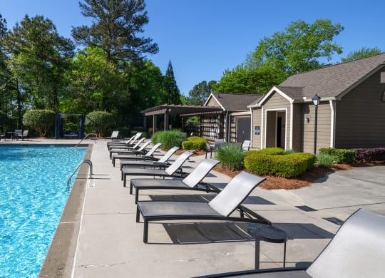 Wynnwood Vinings resident swimming pool with chaise lounge chairs and trees in the background