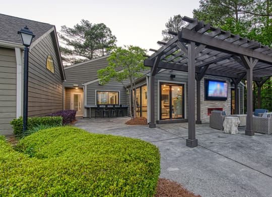 Wynnwood Vinings resident poolside lounge patio with glass entrance door and a pergola and TV with couches