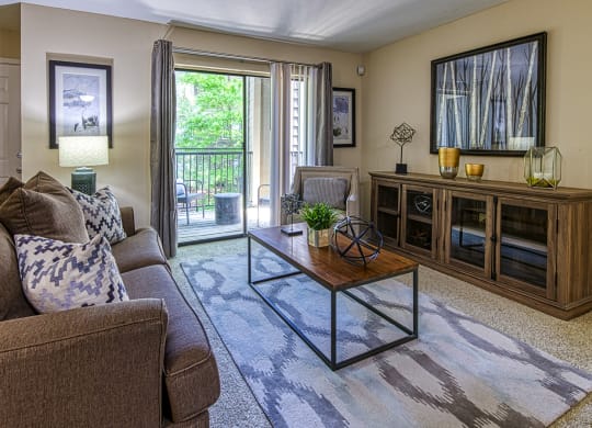 Apartments in Vinings, GA with In-Unit Washer and Dryer - Wynnwood Vinings - Furnished Living Room with Carpet Flooring and a Sliding Glass Door to a Private Balcony