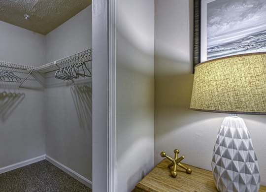 A lamp with a white shade and a gold base sits on a wooden table.