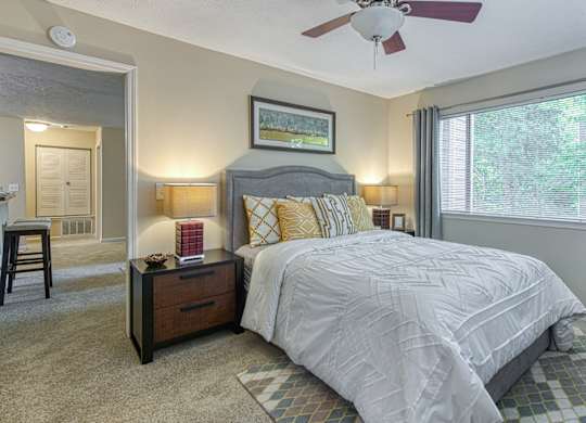 A bedroom with a bed, nightstand, and a ceiling fan.