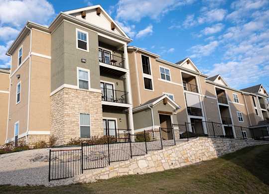 A large apartment complex with a black fence in front.