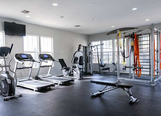 A fitness gym with a variety of equipment including treadmills, weight machines, and a bench press.