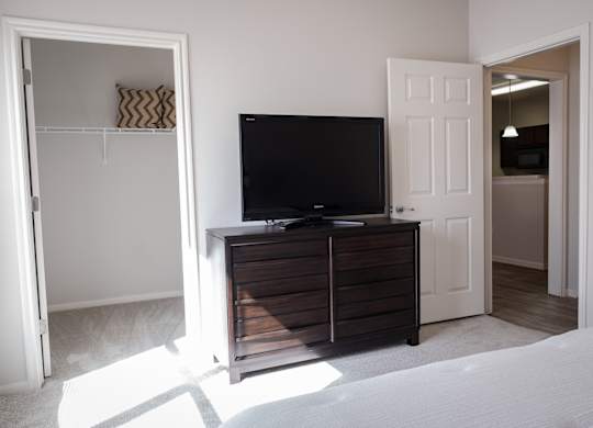 A black TV sits on a wooden cabinet in a room with white walls.