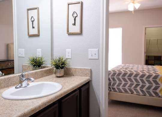 A bathroom with a sink, mirror, and bed.