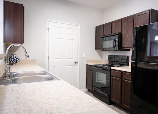 A kitchen with black appliances and brown cabinets.