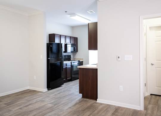 A kitchen area with a black fridge, black microwave, and black oven.