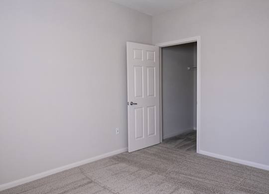 A room with a white door and carpeted floor.