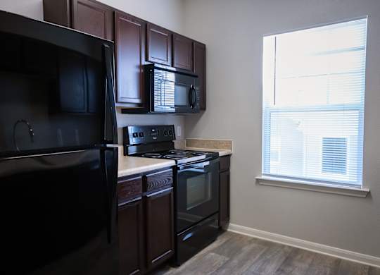 A kitchen with black appliances and brown cabinets.