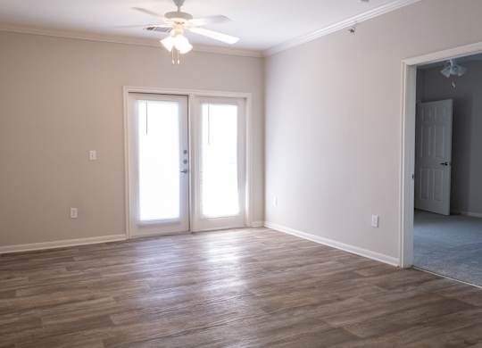 A room with a ceiling fan and sliding glass doors.