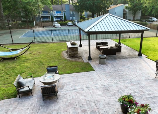 a large paver patio with a gazebo and a hammock next to a