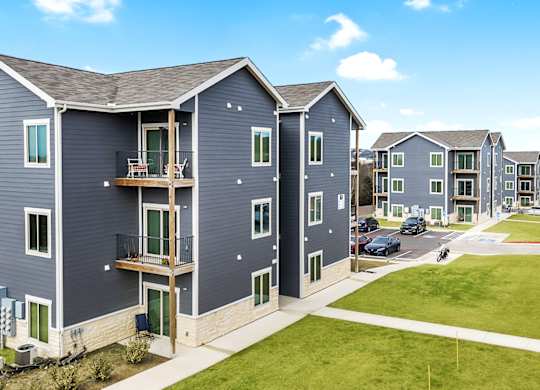 a row of apartments with blue roofs and green grass