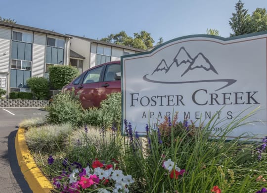 A sign for foster creek apartments with flowers in front of it