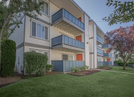 Tukwila, WA Apartments - Foster Creek - Exterior View of Apartment Building with Balconies Surrounded by Lush Landscaping