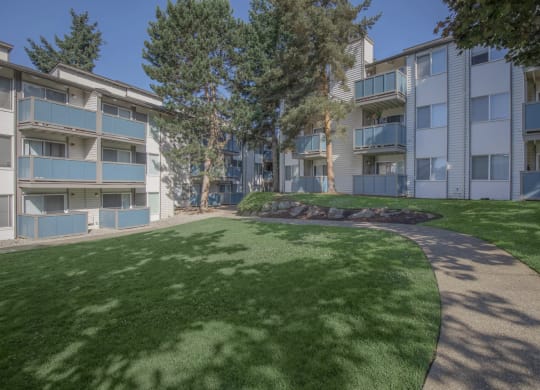 a grassy area with trees in a courtyard space at pet-friendly apartments in Tukwila