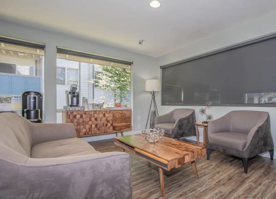 Inside the renovated leasing office at Foster Creek apartments with gray couches and chairs and a wooden coffee table