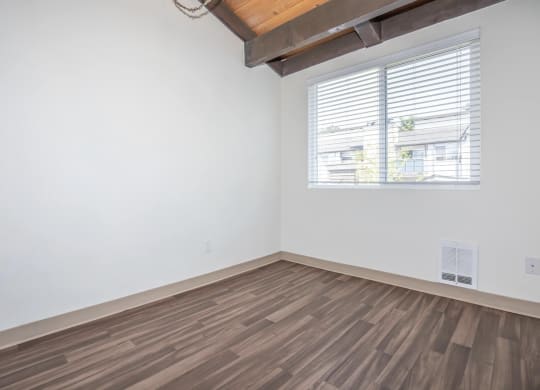 Interior room with hardwood floors, vaulted ceiling and a window and white walls at Foster Creek apartments