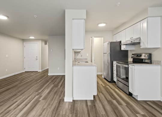 an empty kitchen with white cabinets and a stainless steel stove and refrigerator