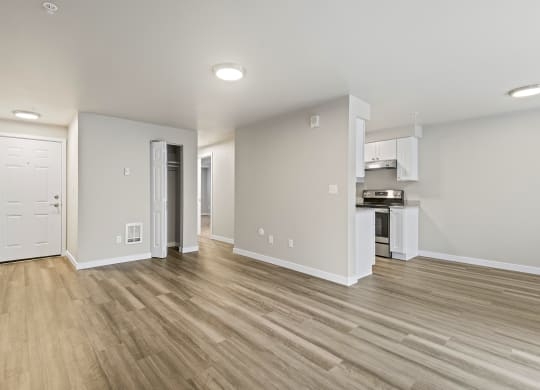 a renovated living room with wood flooring and a kitchen