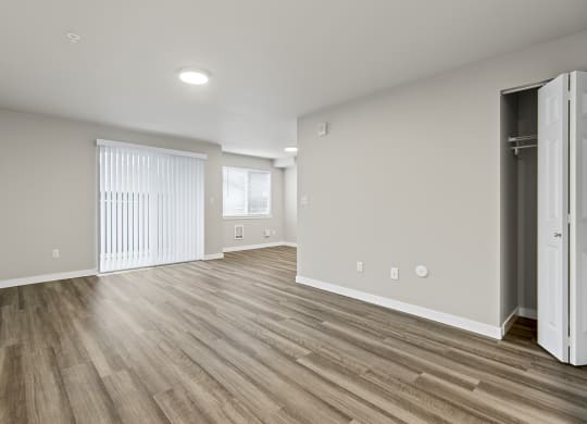 an empty living room with hardwood flooring and a closet