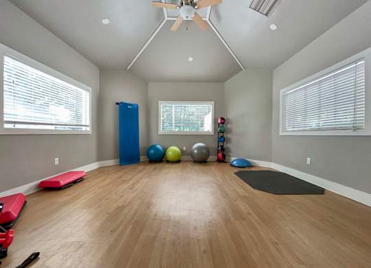 a yoga room with yoga mats and a ceiling fan