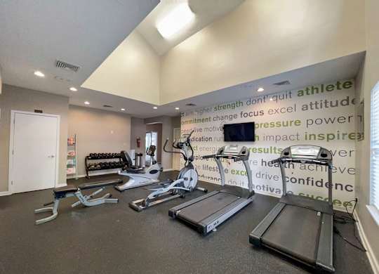 a gym with weights and a monitor on the wall