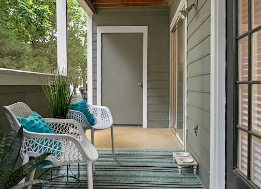 a front porch with two chairs and a door