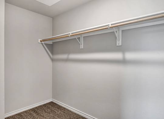 our spacious closets in our apartments have a large closet with a white wall and