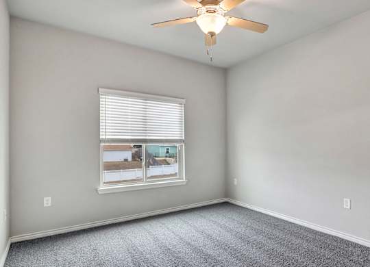 an empty bedroom with a ceiling fan and a window