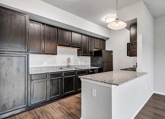 an empty kitchen with dark cabinets and granite counter tops