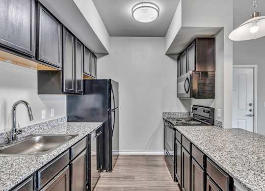 an empty kitchen with granite counter tops and a stainless steel refrigerator