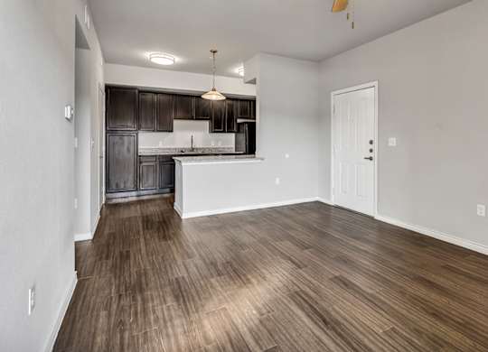 the living room and kitchen of an empty apartment with wood flooring