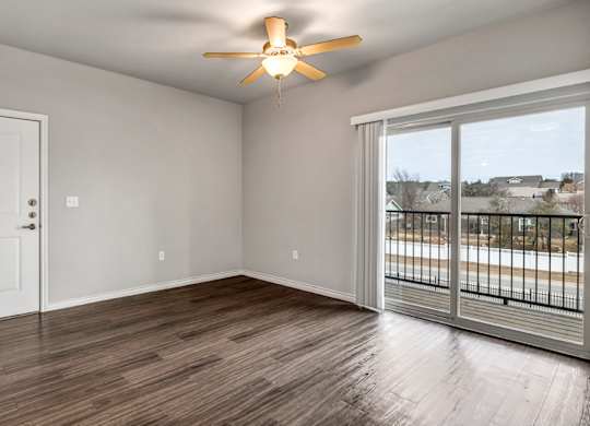 an empty living room with a balcony and a ceiling fan