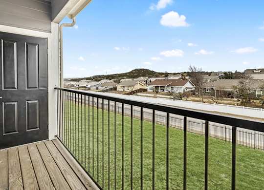 the view from the balcony of a home with a door open to a yard