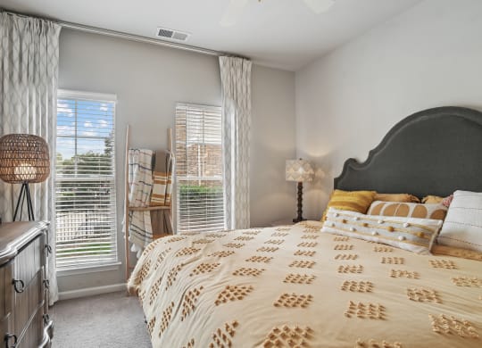 a bedroom with a large bed and two windows