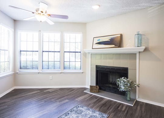 an empty living room with a fireplace and windows