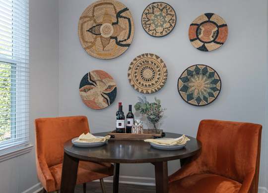 a dining area Seasons at Umstead apartments in Raleigh with a table and two orange chairs