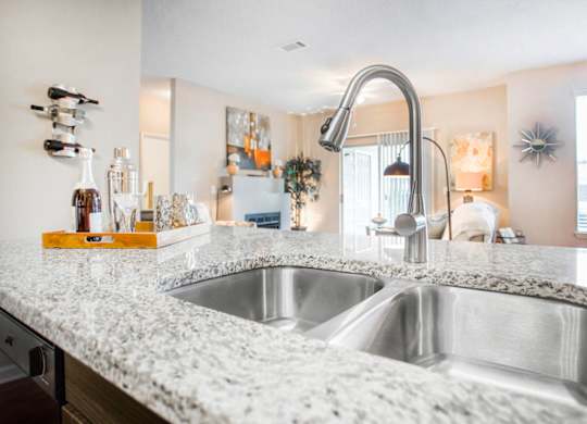 A kitchen with a marble countertop and a stainless steel sink.