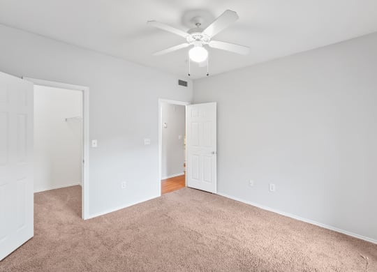 a bedroom with gray carpet and a white ceiling fan