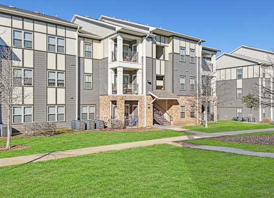 an exterior view of an apartment building with green grass and sidewalks