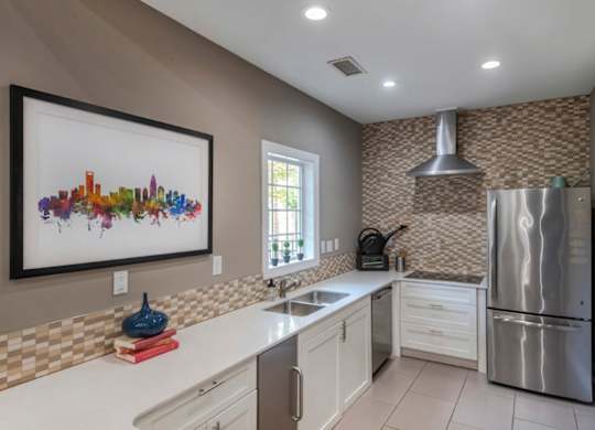 A kitchen with a stainless steel refrigerator and a cityscape picture on the wall.