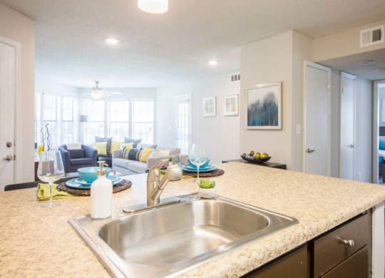 a kitchen counter top with a sink and a living room
