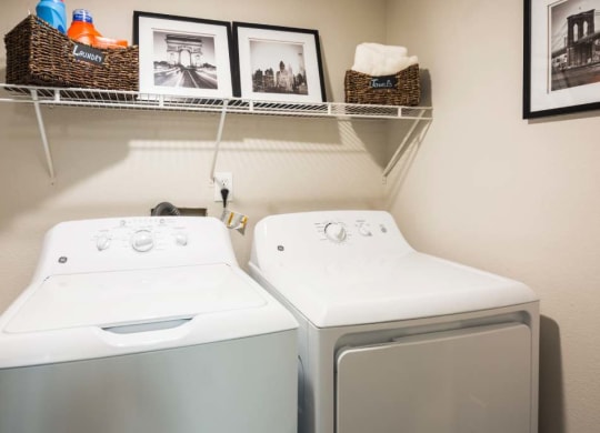a washer and dryer in a laundry room with pictures on the wall