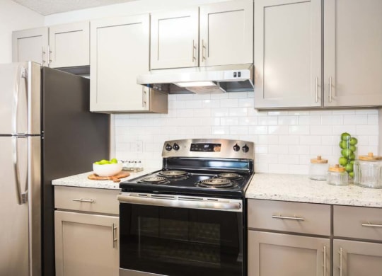 Renovated kitchen with stainless steel appliances and gray cabinets at Eclipse Apartments