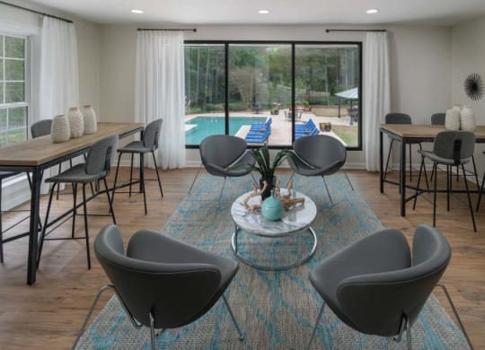 Veridian at Sandy Springs apartments leasing center resident clubhouse interior with tables and chairs and a pool in the background