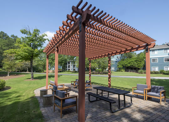 a patio with a picnic table and chairs under a pergola at Wynnwood Vinings apartments