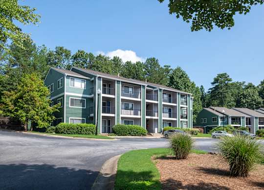 Apartment complex with green trees and a clear blue sky.