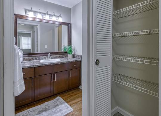 A bathroom with a large mirror, sink, and wooden cabinets.
