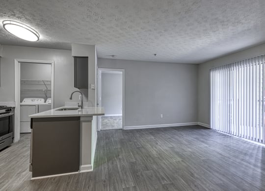 an empty living room and kitchen with a large window