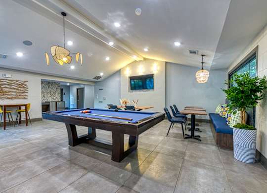 A room with a pool table and a tv mounted on the wall.